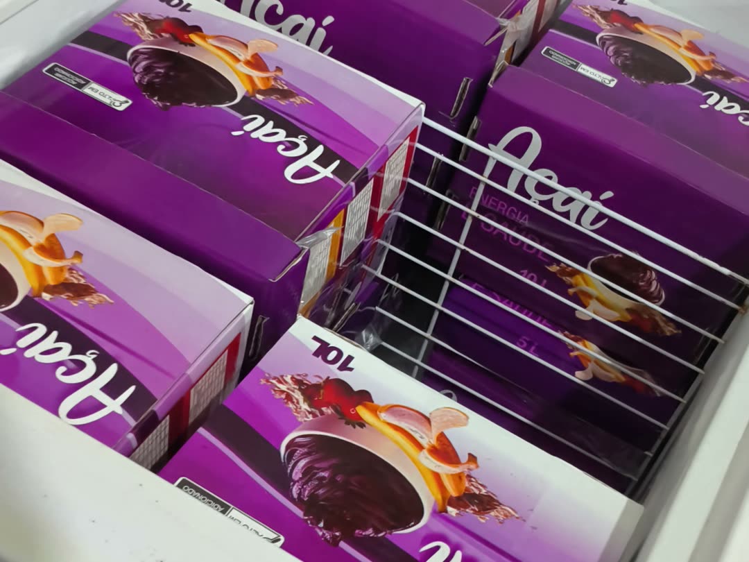 Freezer da fábrica Algo Mais com caixas de açaí de 10 litros em pé, estoque pronto para as rotas de entrega da semana
