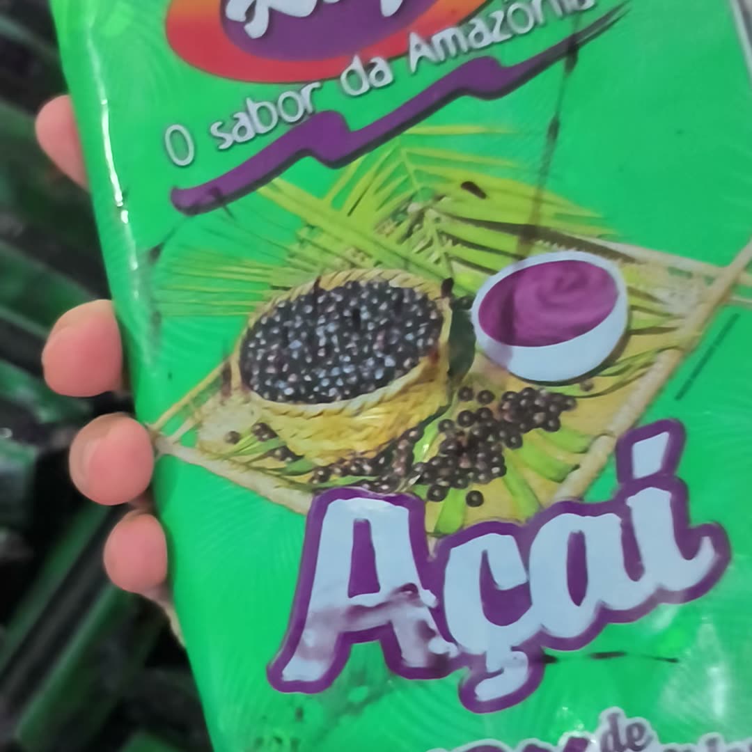 Sachê de polpa de açaí com 12% de sólidos totais na mão, dentro do freezer de matéria-prima da fábrica Algo Mais