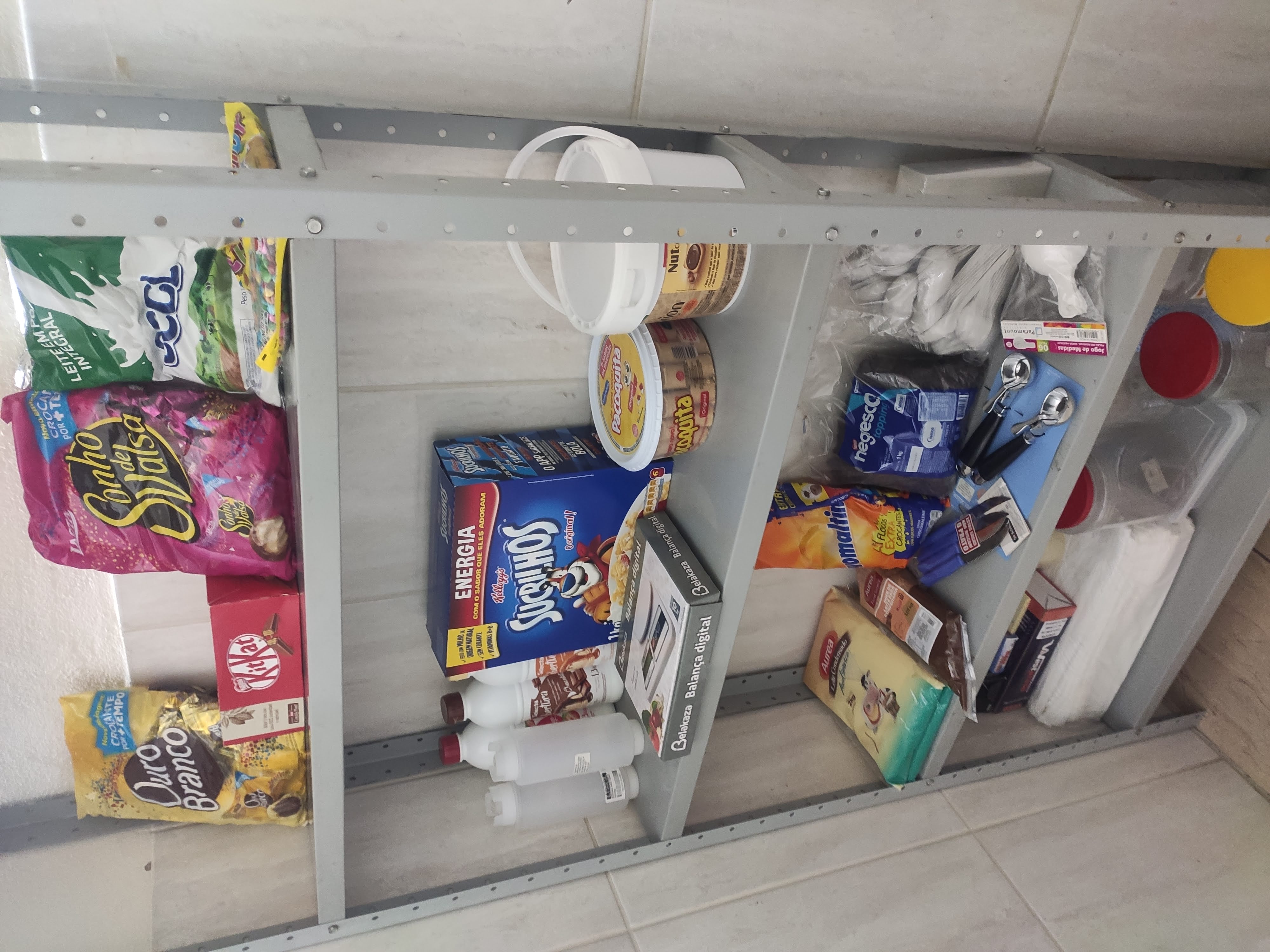 Prateleira de insumos da operação inicial em 2020 — Sonho de Valsa, Ouro Branco, Sucrilhos, balança digital e dispensers organizados